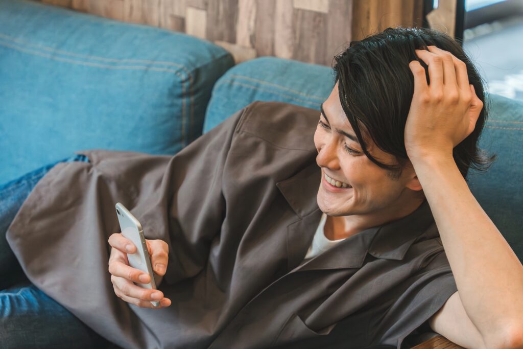 スマホをいじりながら笑顔の男性