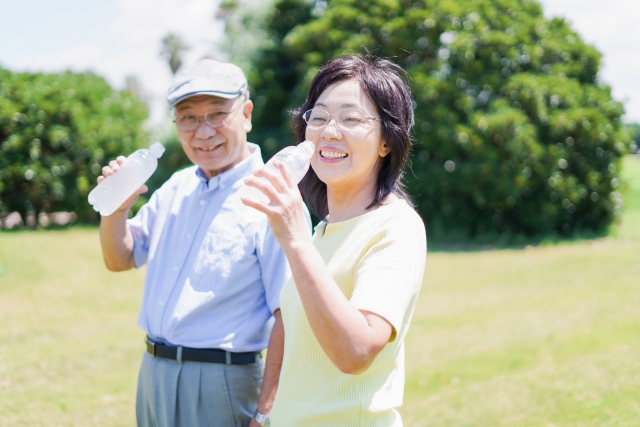 外で水を飲む高齢者夫婦