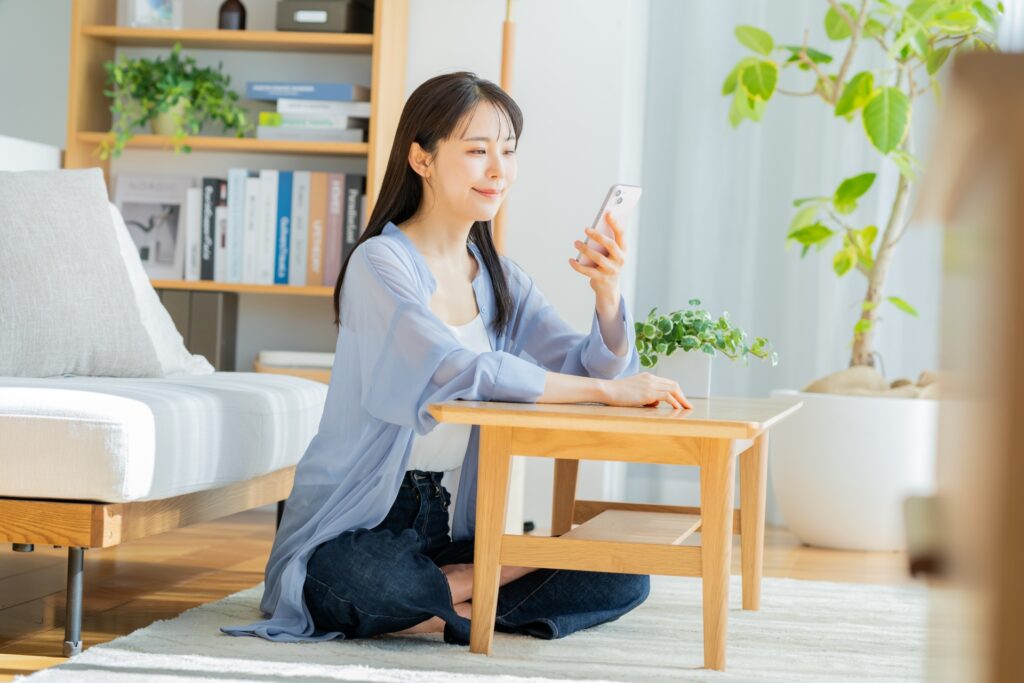 部屋でスマホを見る女性