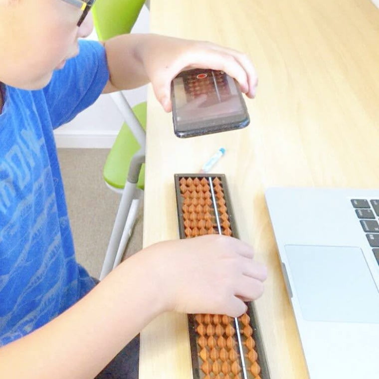 スマホでそろばんを撮影する子ども