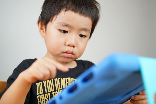 真剣な顔でタブレットにタッチする子ども